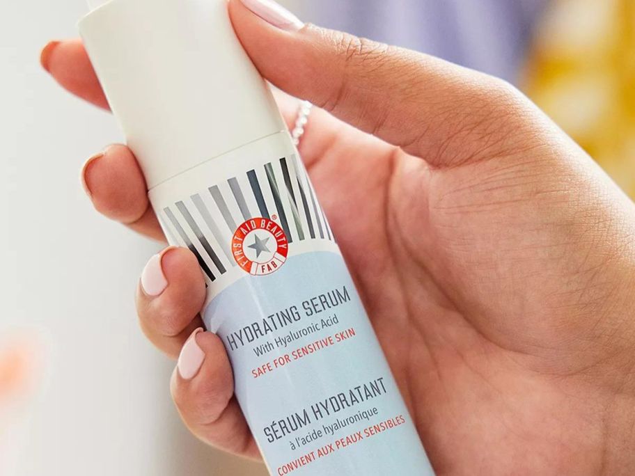 Hand holding a bottle of First Aid Beauty Hydrating Serum