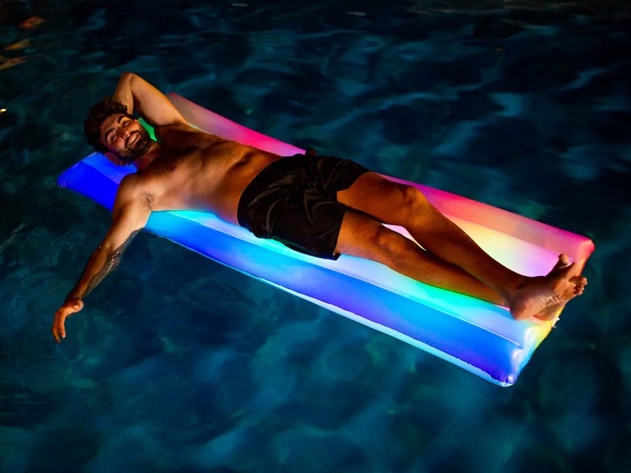 man laying on rainbow led pool float