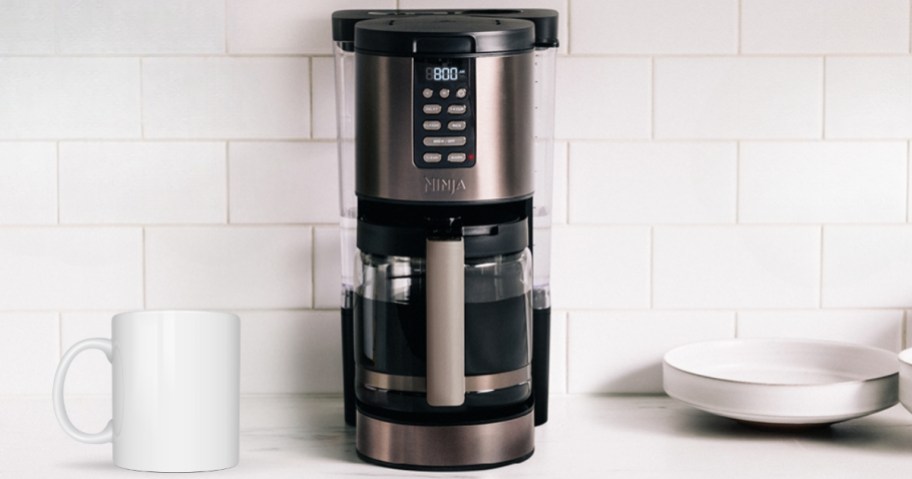 black and stainless steel Ninja programable coffee maker on a kitchen counter with white subway tile backsplash