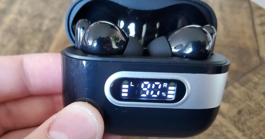 hand holding a pair of wireless earbuds in a charging case, case shows 90% charged