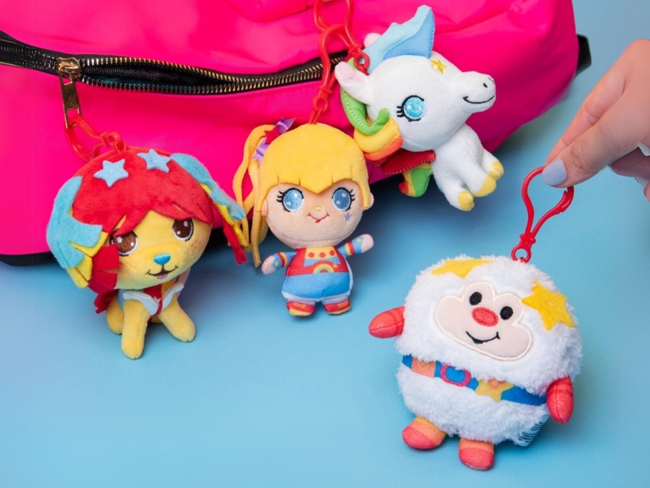 Rainbow Brite plush backpack clips in various figures with a pink backpack behind them