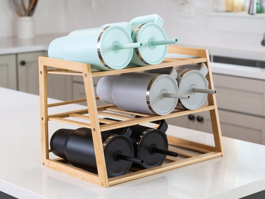 bamboo 3 tier water bottle or tumbler organizer on a counter with large tumblers in it