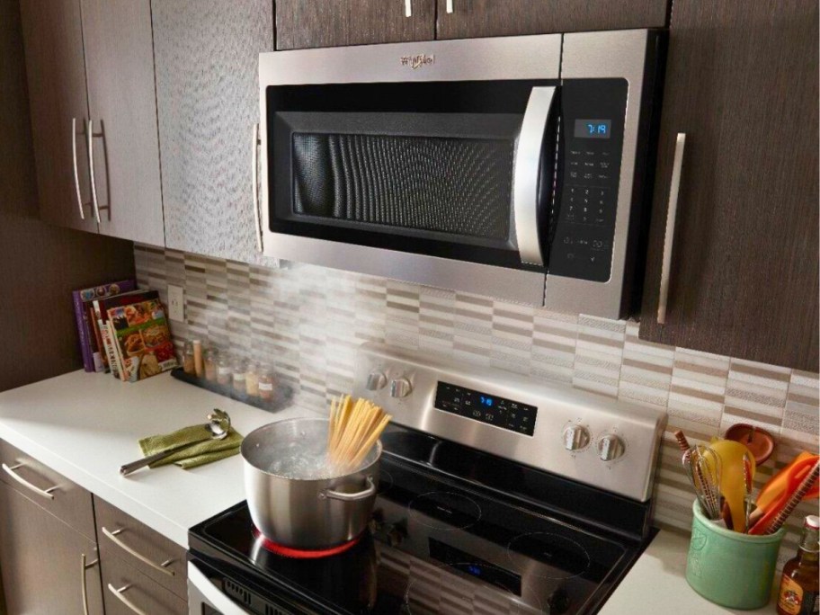 stainless steel microwave above a stove inbetween cabinets