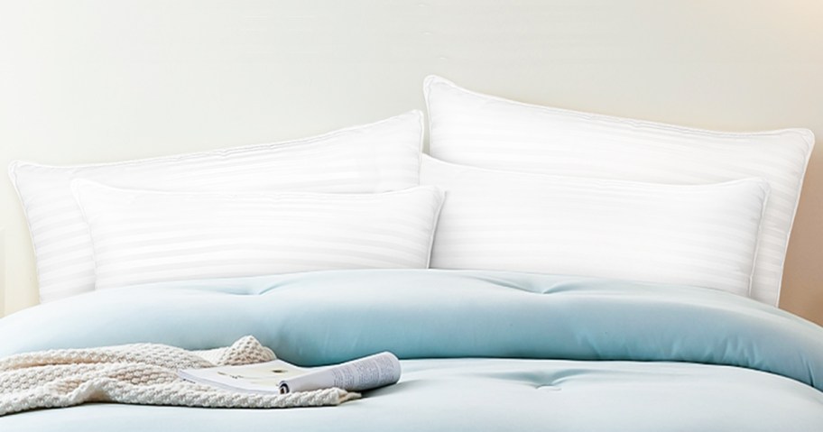 four white pillows on a bed with blue bedding