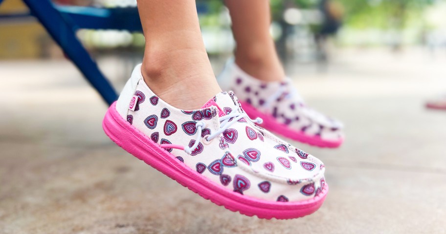 girl wearing a pair of pink and white heart print sneakers