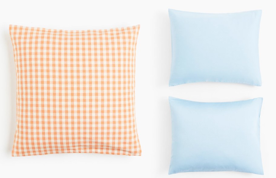 orange and white checkered pillowcase and two blue pillowcases