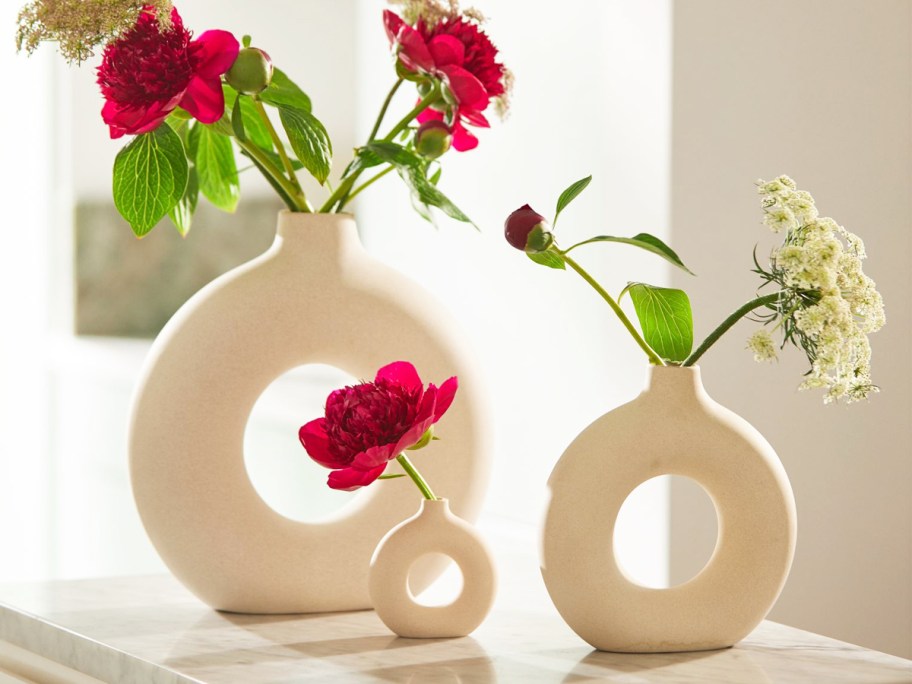 white circular vases with red and white flowers inside