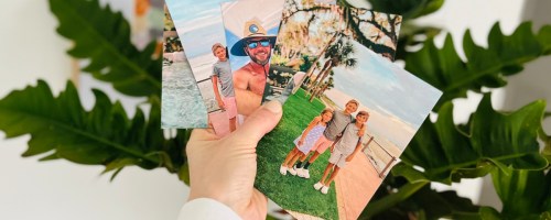 Hand holding magnets photos in front of a plant