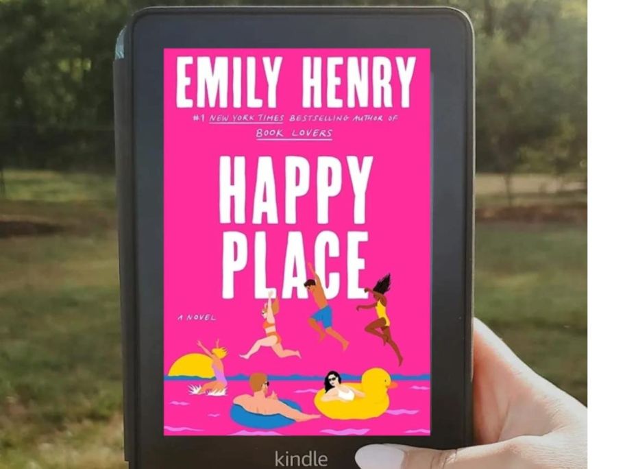 Hand holding a Kindle with Happy Place book displayed on the screen