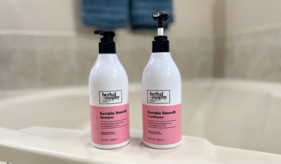 Herbalosophy Biotin + Collagen Shampoo and Conditioner on the side of a bathtub
