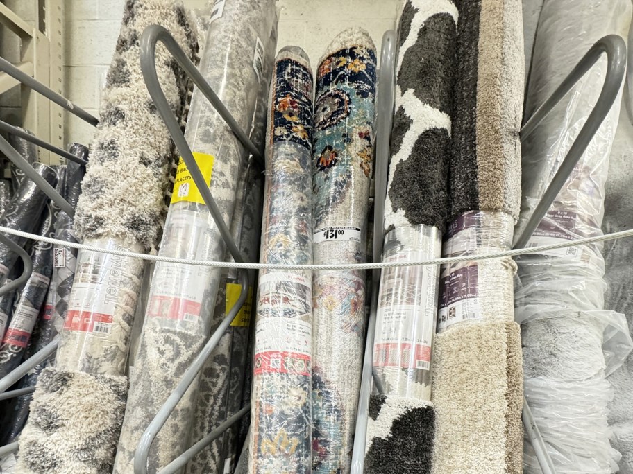 store display of rolled up area rugs in various colors