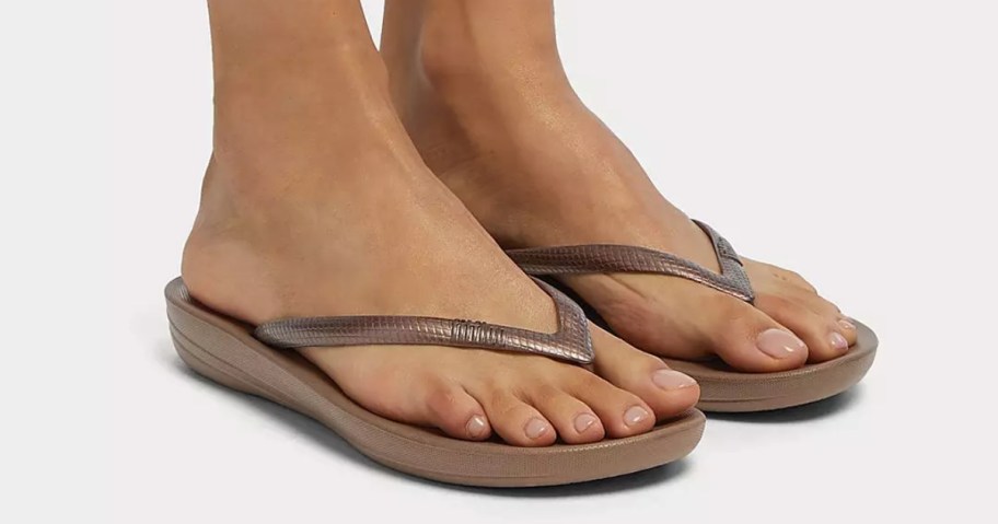 woman's feet wearing bronze flip flops