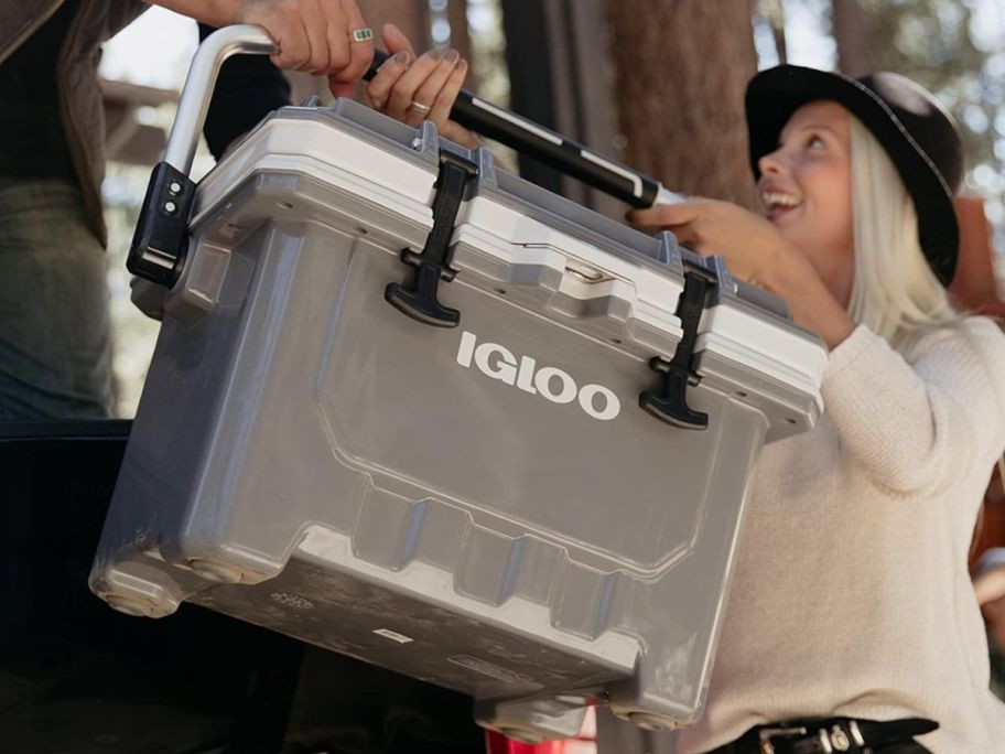 People carrying a large Igloo cooler