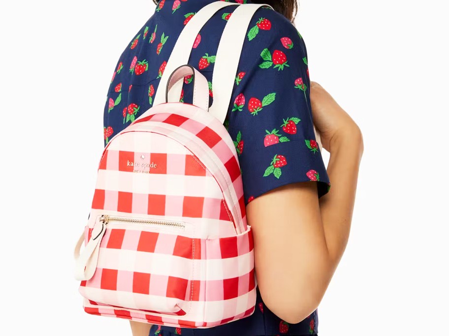 woman carrying a red, pink, and white gingham print mini backpack