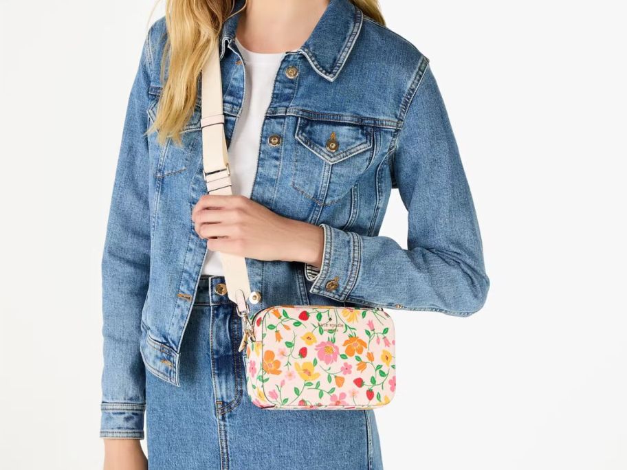 A woman in denim holding a Kate Spade purse with flowers