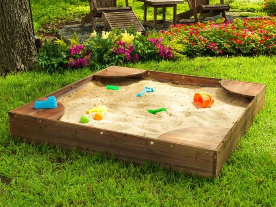 A kidkraft wooden sandbox with toys in it