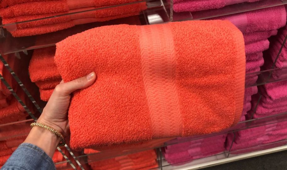 a womans hand holding an orange bath towel