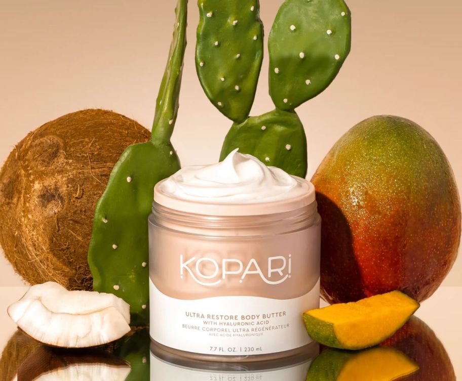 a jar of body butter pictured with a cactus, coco nut and mango