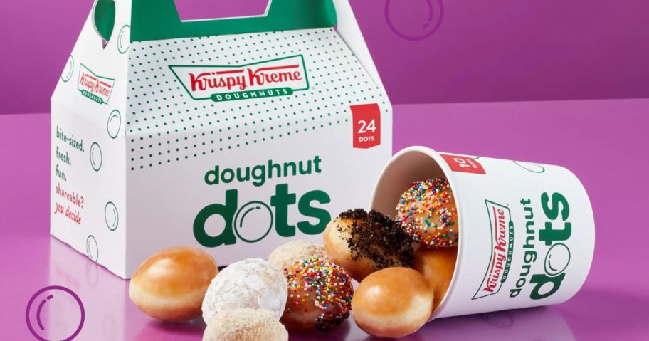 A box and a cup of Krispy Kreme Doughnut dots in assorted flavors with the cup laying on it's side and doughnuts spilling out of it