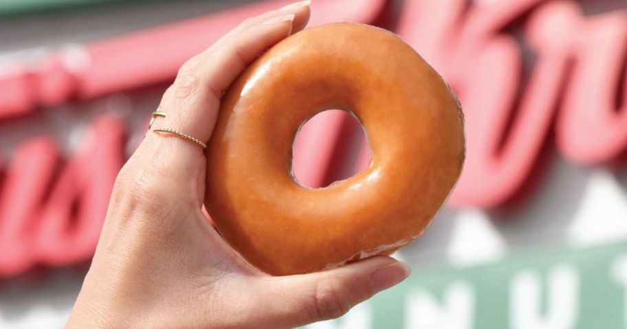 Hand holding a Krispy Kreme Original Glazed doughnut