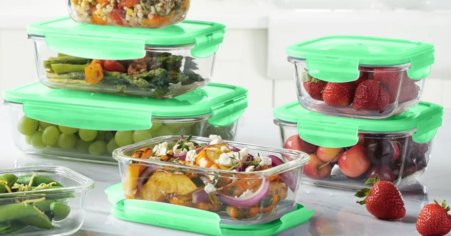 glass food storage set with green lids filled with various foods on counter