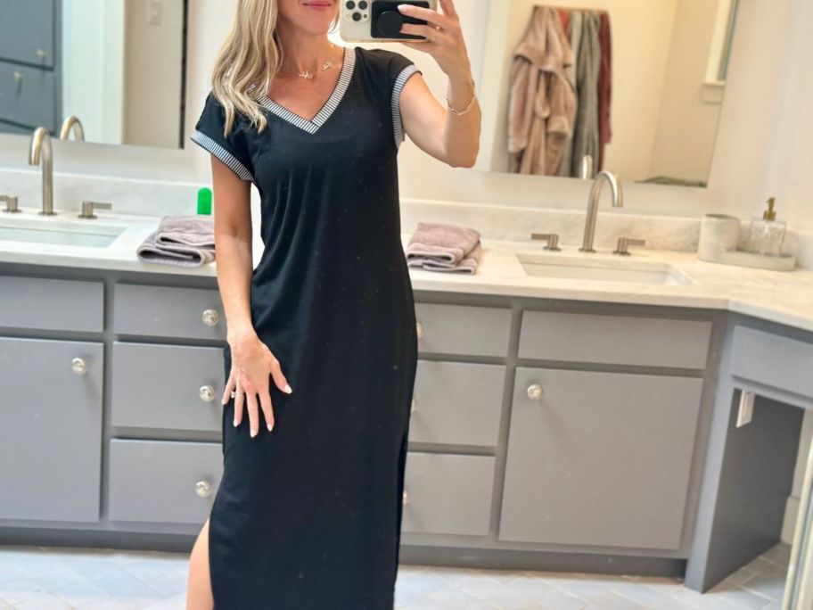 A woman wearing a long, black dress in her bathroom 