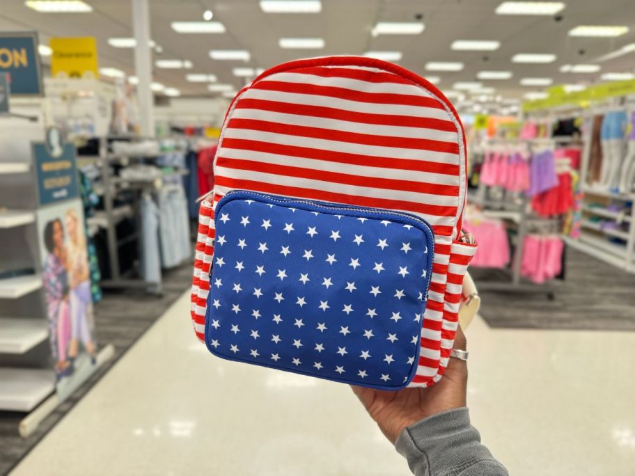 A hand holding a Mad Love Americana Backpack at Target