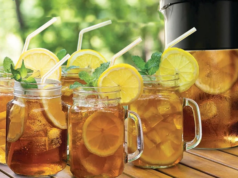 four mugs of iced tea with lemon wheels and straws