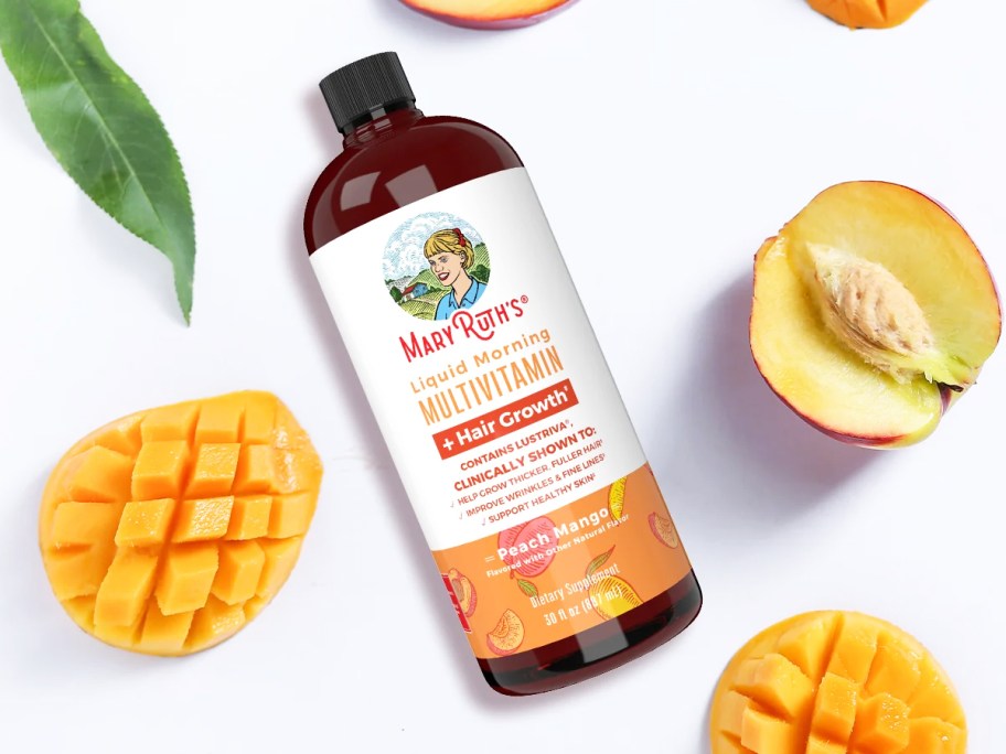 bottle of MaryRuth's Liquid Multivitamin + Lustriva Hair Growth surrounded by cut peaches and mangoes