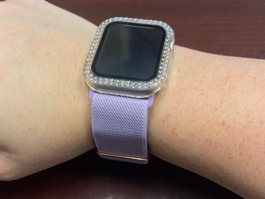 An arm with an Apple Watch and purple watch band