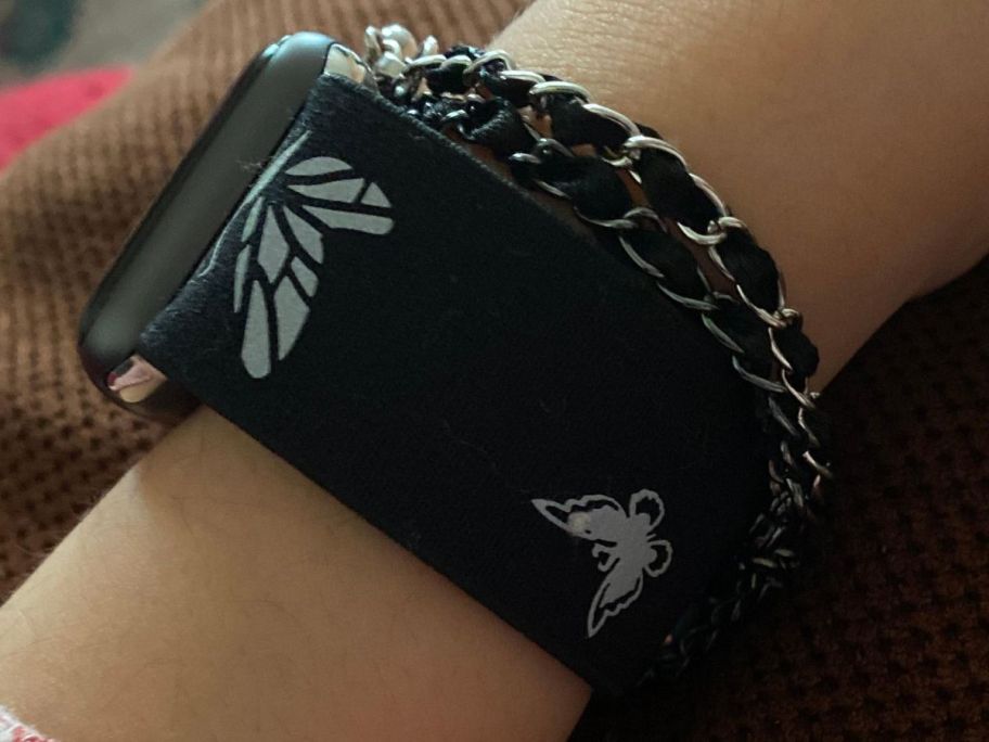 An arm wearing a black and white butterfly style Apple Watch Band