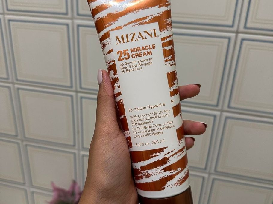 Hand holding a Tube of Mizani Miracle Hair Cream