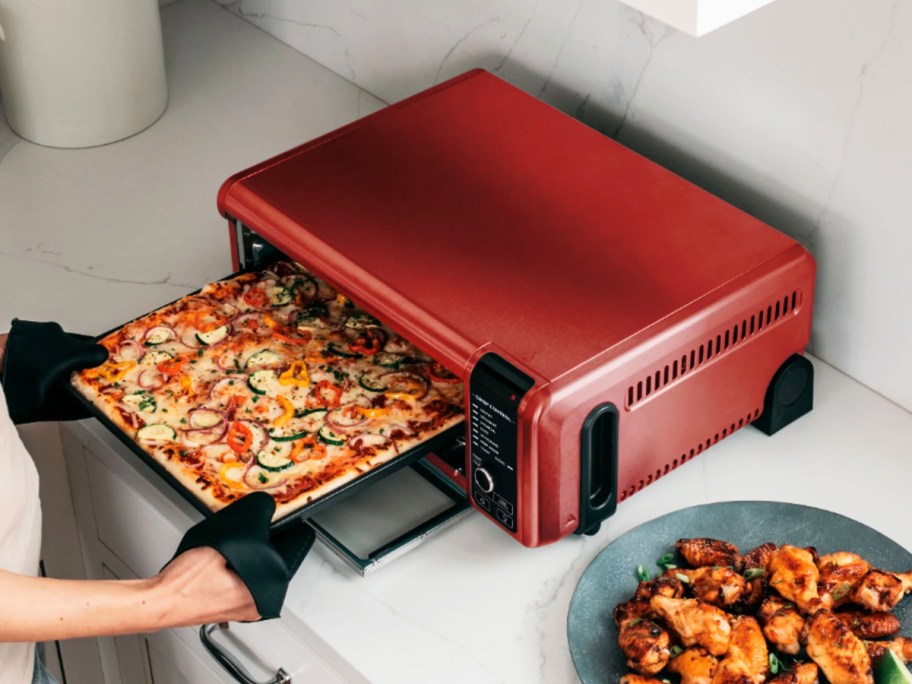 taking pizza out of a red ninja foodi oven