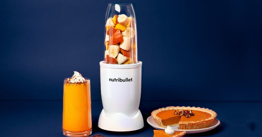 A nutribullet Pro Blender with Pumpkin Pie smoothie ingredients in it next to a Pumpkin pie