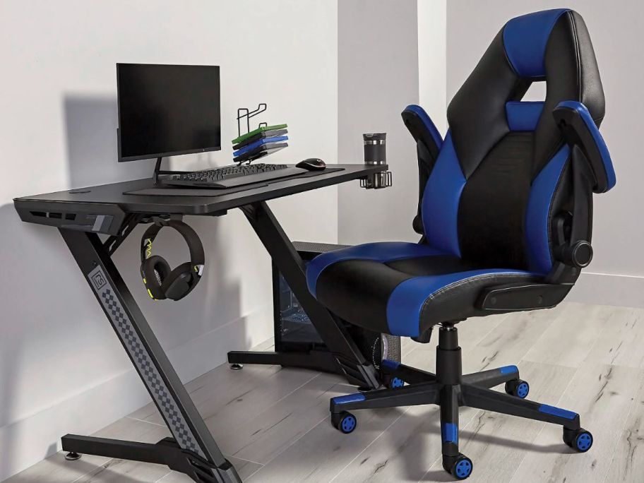 An Office Xdepot gaming chair next to a computer desk with gaming equipment