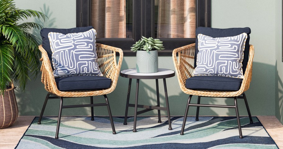 two wicker patio chairs with navy blue cushions, throw pillows, and side table