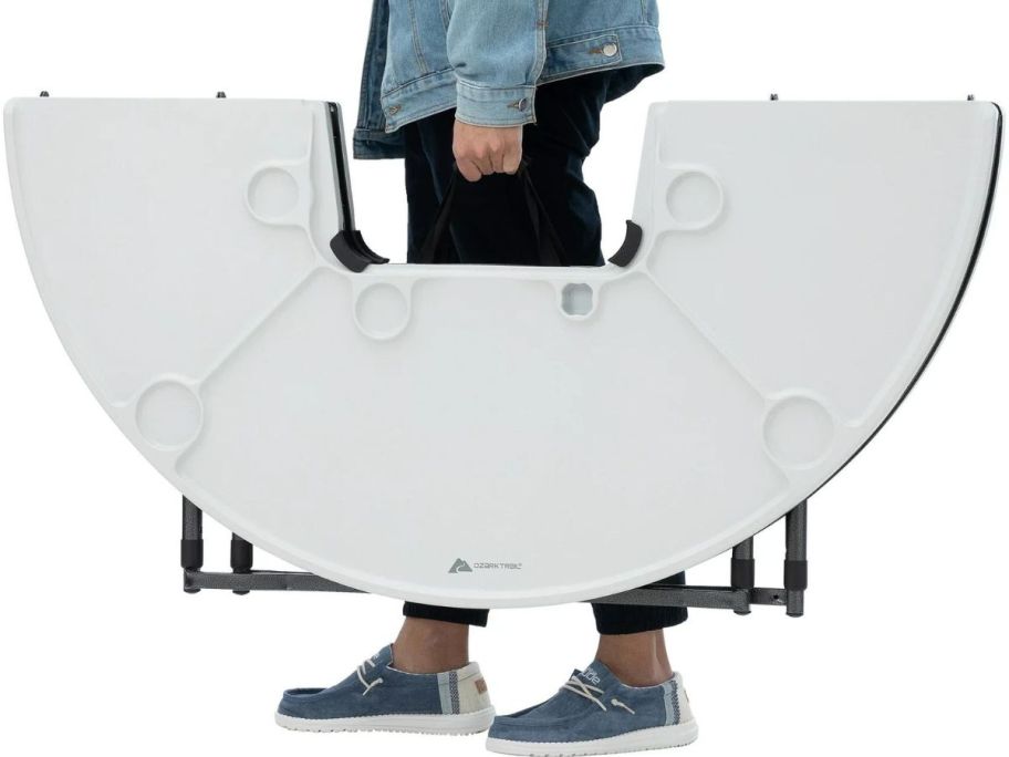 Stock image of a person carrying a folded Ozark Trail camping table