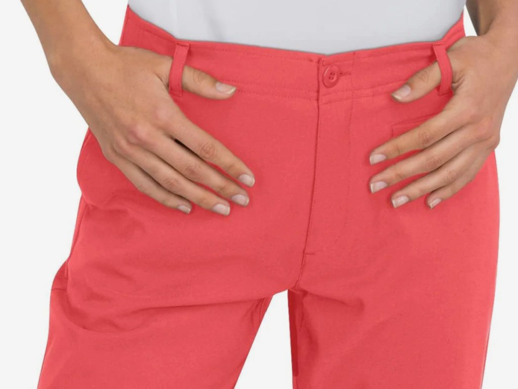 women holding onto belt loops of pink golf pants