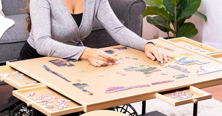 woman putting together puzzle on a puzzle table with drawers