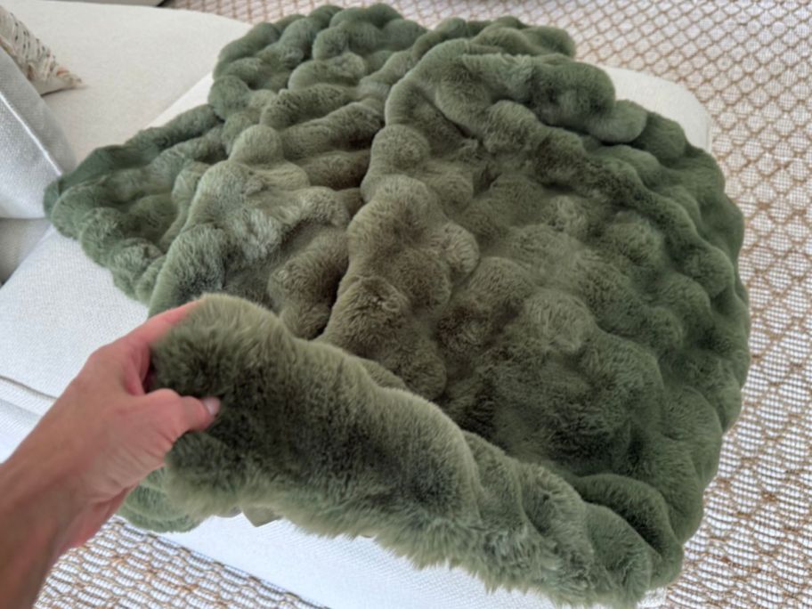 Hand touching a Quince faux fur throw blanket