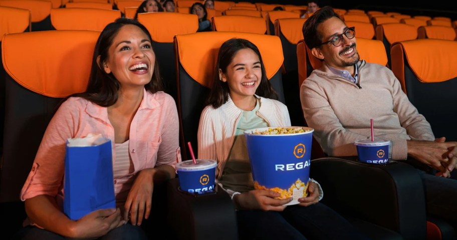 family watching movie at Regal Cinemas and holding popcorn and drinks