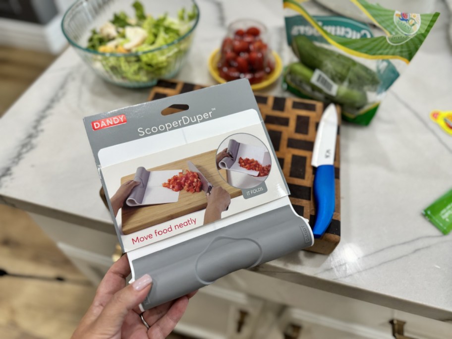 The ScooperDuper kitchen gadget next to a cutting board of vegetables