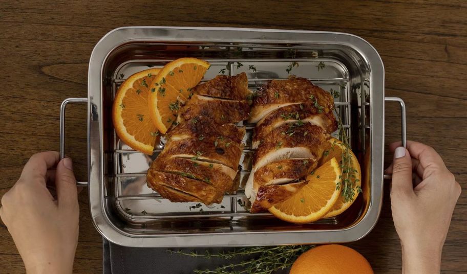 a roasting pan with sliced roasted chicken breasts and orange rings