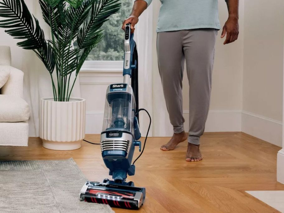 man using a Shark Stratos Upright Vacuum w/ DuoClean PowerFins HairPro to clean hardwood flooring