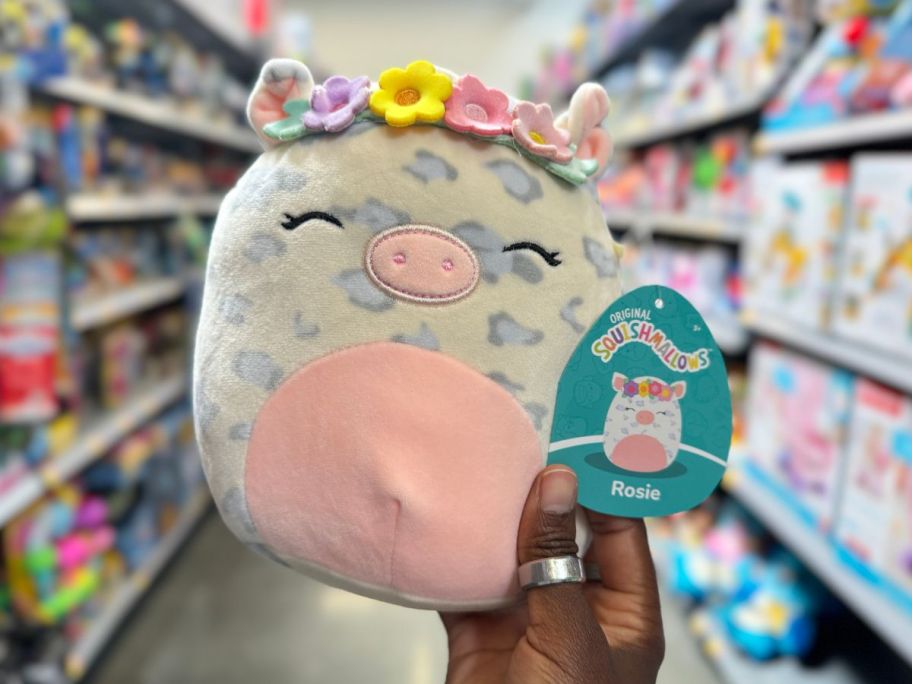 A hand holding a Squishmallows Rosie