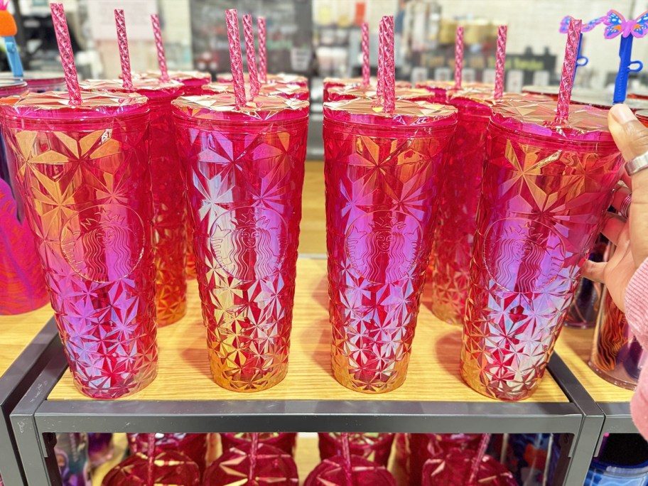 row of bright pink iridescent starbucks tumblers on display in store