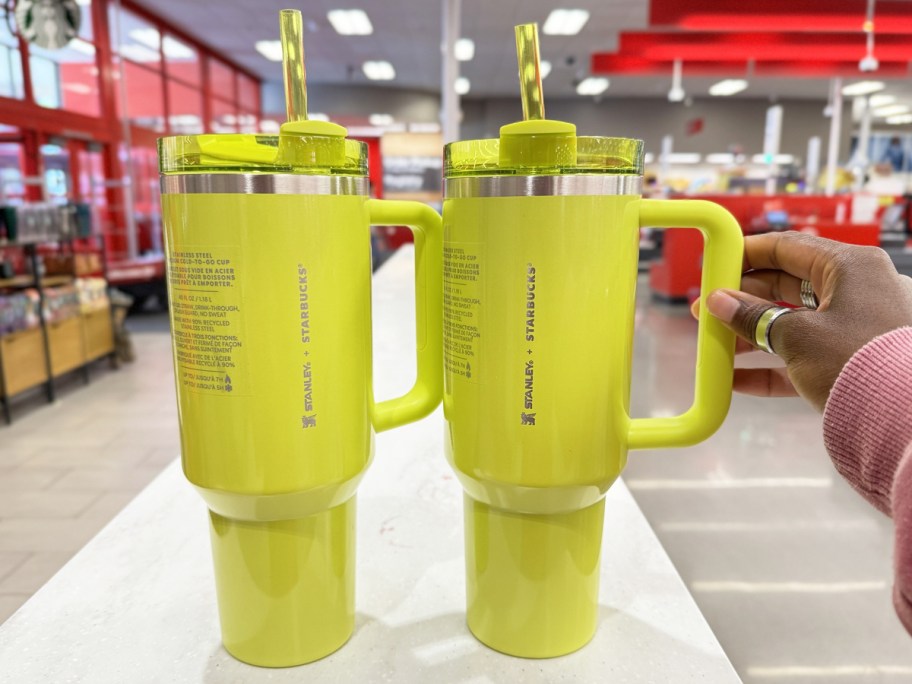 hand touching handle on bright yellow stanley tumbler