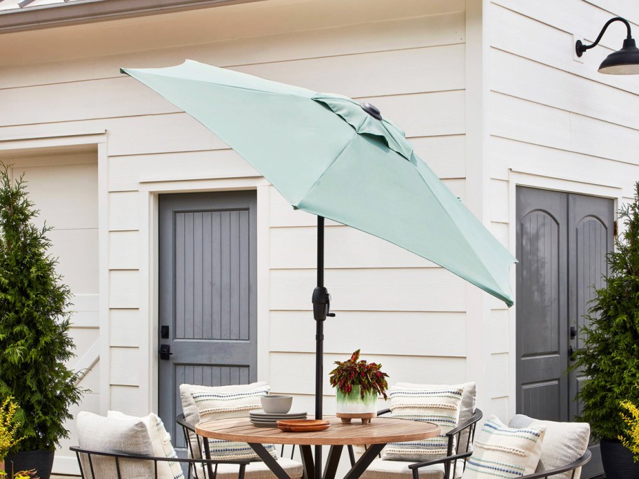 light blue patio tilt umbrella covering a patio set in backyard