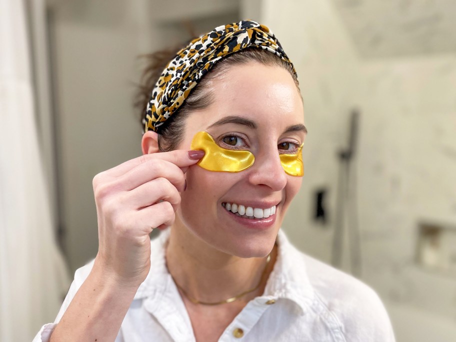 woman applying gold eye gels to her face