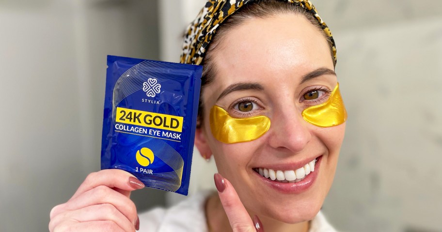 woman wearing a set of gold under eye patches and holding packaging up next to her face